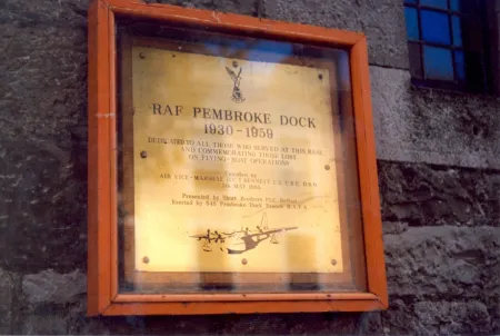 Plaque in wooden case, fixed to wall.