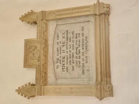 A marble tablet with a cream decorated surround with the impression of an anchor and coiled rope.