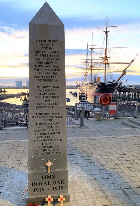 Obelisk memorial for HMS Royal Oak with HMS Warrior behind it.