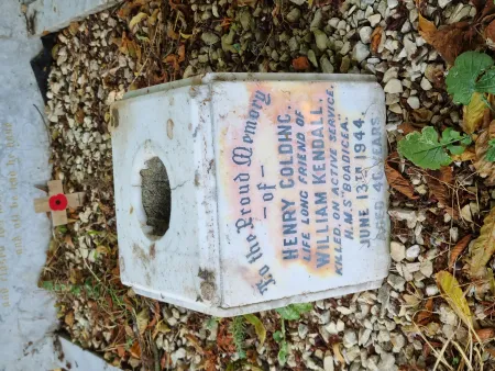 A square marble flower holder in the gravelled area of a kerbed grave