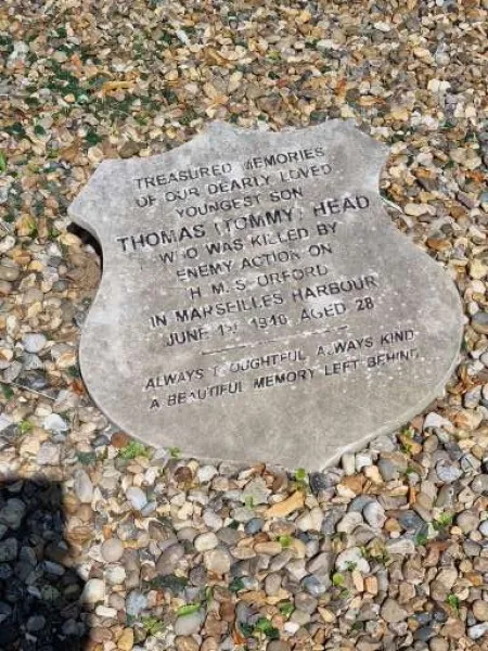 A shield shaped stone tablet in the gravelled centre of a kerbed family grave.