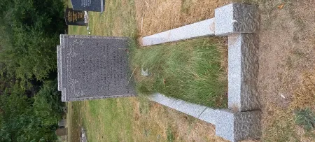 Grey granite headstone at head of kerbed grave