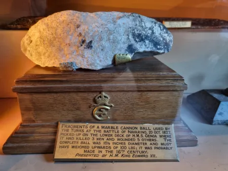 Fragment of a marble cannon ball. The complete ball weighed 100 pounds, and was 10.5 inches in diameter. Probably made in the sixteenth century and fired by the Turkish at the Battle of Navarino; found at the deck of HMS Genoa, 20 October 1827.