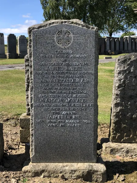 Granite family gravestone, with a Celtic cross above commemorations