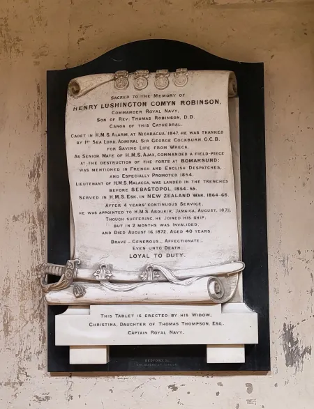 White stone carved in the form of a scroll, black lettering with carved sword below