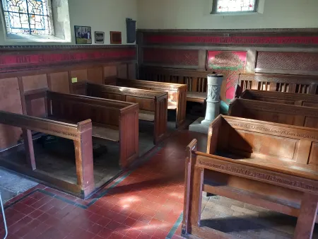 Wooden pews in stone church showing memorial engraving