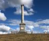 Column on hilltop against sky background