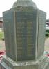 Tall cross with a sword of sacrifice standing on an octagonal plinth and four stepped octagonal base. The names on the slate tablets are picked out in gold lettering.