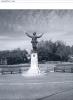 Statue of soldier with raised hands on plinth.