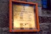 Plaque in wooden case, fixed to wall.