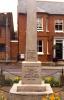 Obelisk in front of brick house.