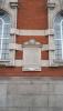 Stone plaque on a curved brick wall of a building between two windows.