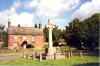 Cross with brick building in the background.