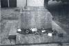  A limestone wheel cross on a stepped and battered rectangular stone pedestal and rectangular base, with additional stone tablets at each of the four faces of the base.