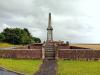 Obelisk set on a tapering plinth with the dedication and names in black lettering on each face. Stone wall surrounding. 