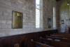 Brass plaque fixed to stone wall.