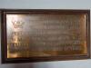 Engraved metal plaque in a wooden frame.