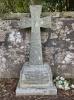 Granite gravestone topped with a cross, and backed against a wall