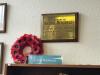 Brass wall plaque on wooden backboard.