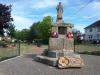 Sculpture of serviceman standing atop two deep octagovalsteps and large, rough stone pieces
