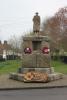 Sculpture of serviceman standing atop two deep octagovalsteps and large, rough stone pieces