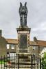 Metal winged angle of peace atop stone pillar with plaques attached