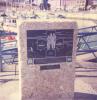 Metal plaque with incised figures, attached to rough stone pillar near marina