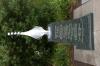 Black granite pillar with metal sculpture on top, with inscriptions on sides of each