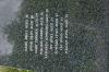 Black granite pillar with metal sculpture on top, with inscriptions on sides of each