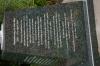 Black granite pillar with metal sculpture on top, with inscriptions on sides of each