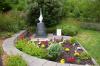 Black granite pillar with metal sculpture on top, with inscriptions on sides of each