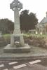 Wheel cross on tapering plinth with low stone wall behind