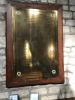Brass plaque on wooden backboard, showing names of the fallen in three columns.
