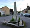 Another side view of a stone obelisk on a small island at a road junction
