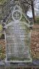 An arched gravestone with a foliated decoration above the inscription with four names engraved in addition to that remembered.