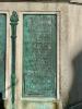 Five bronze plaques mounted on each side of large stone plinth