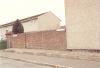 Brick wall in front of a grey coloured house