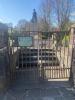 Main entrance to the memorial which has a small gate and a sign with rules aimed at the public.
