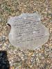 A shield shaped stone tablet in the gravelled centre of a kerbed family grave.