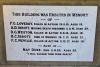 Rectangular white stone plaque with black lettering.