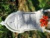 A white marble gravestone in a kerbed plot with an equilateral top with foliated decoration and an engraved Victoria Cross and one name in addition to that remembered.