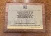 Brass plaque mounted on wood