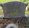 A stone gravestone with an oval top and shoulders and two names in addition to that remembered