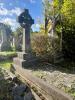Grey granite Celtic cross set atop a plinth composed of two square blocks of decreasing size. The memorial is at the head of a single kerbed grave infilled with concrete. 'Thy Will Be Done' is engraved around the ring of the cross.