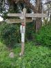 Wooden fingerpost with 4 place names on fingers in country location, with memorial stone at base. Poppy and laminated sheets detailing commemoration 
