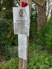 Laminated paper sheets on fingerpost detailing commemoration of  memorial stone and 2 poems authored by the commemorated 