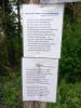 Laminated paper sheets on fingerpost noting 2 poems written by the commemorated 