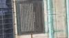 One of the wall mounted metal plaques with inscriptions in relief, on rusticated stone walls at bottom of tower.