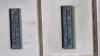 One of the wall mounted metal plaques with inscriptions in relief, on rusticated stone walls at bottom of tower.