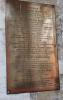 A brass family plaque with gold and red lettering and five names in addition to that remembered